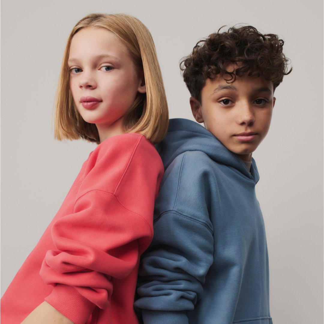 Two young children in colourful clothing on a neutral background