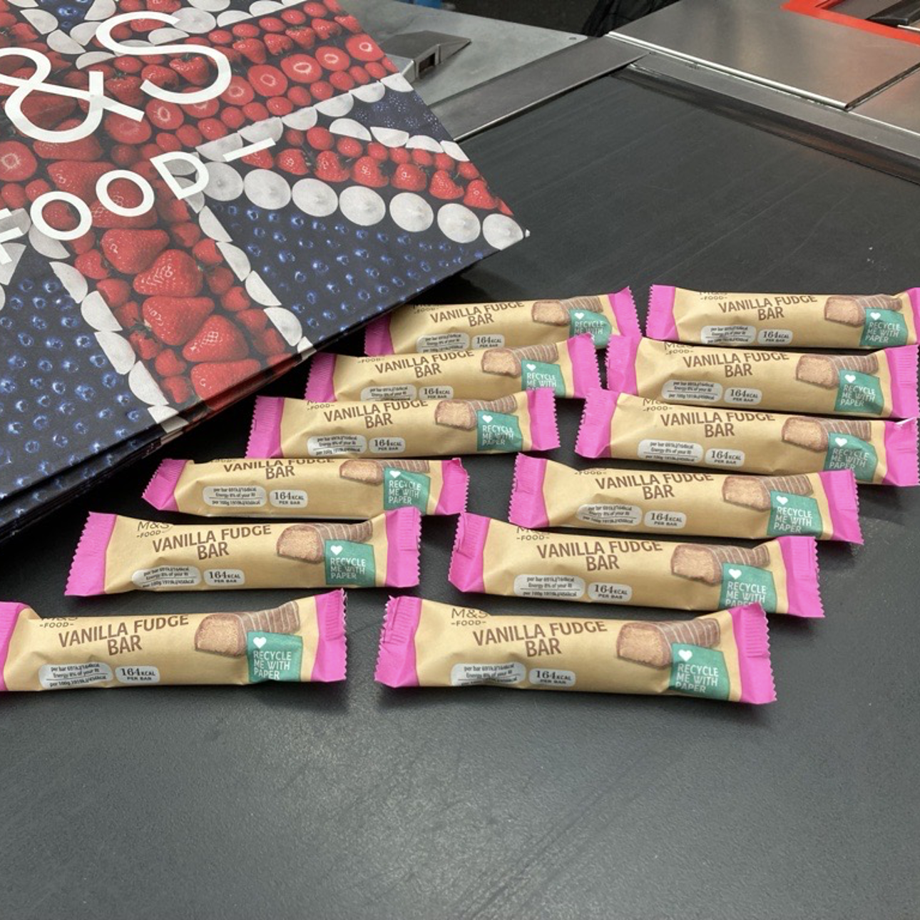 Multiple M&S vanilla fudge chocolate bars laid out at a supermarket checkout