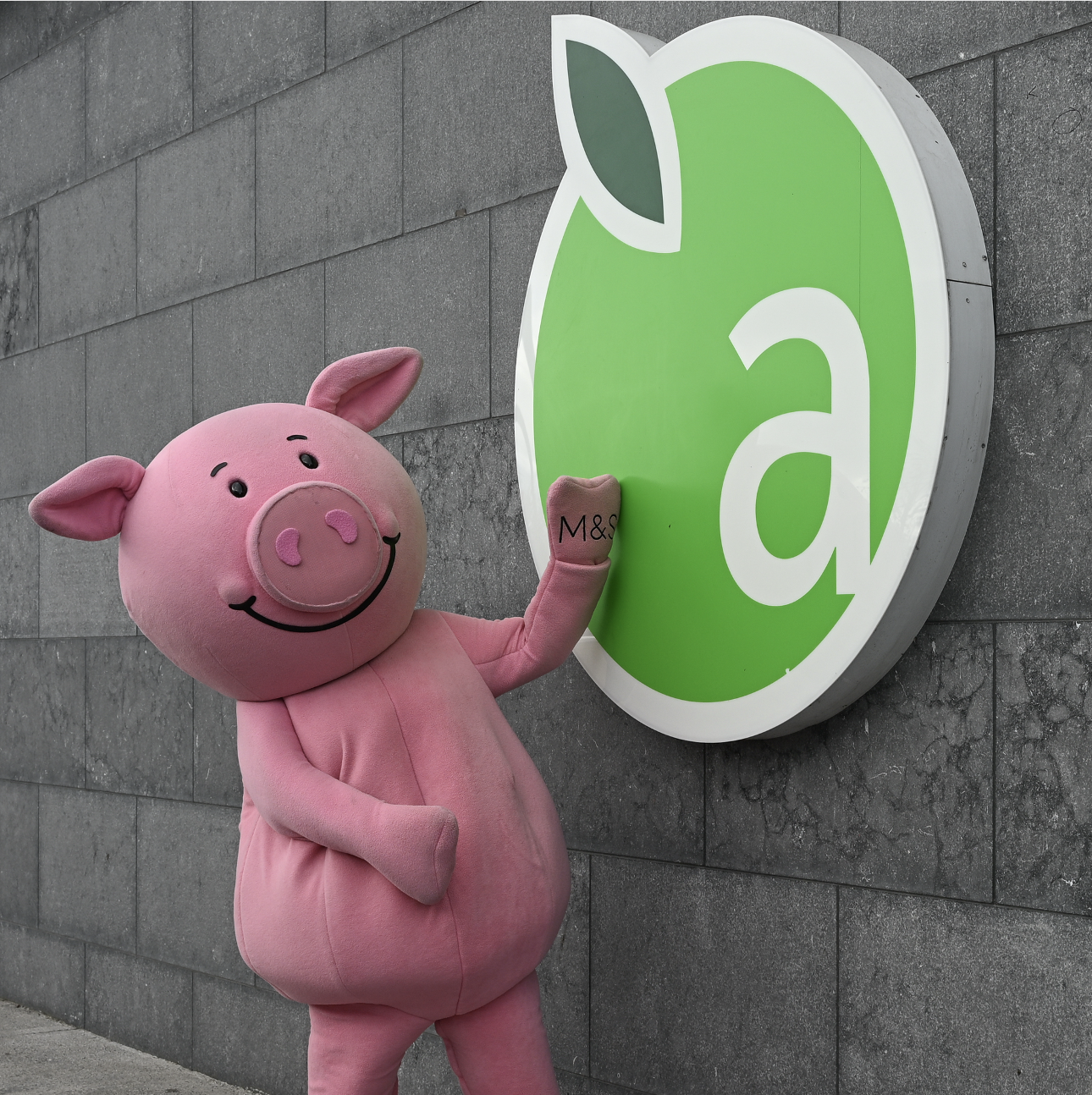 Percy Pig standing next to the Applegreen logo