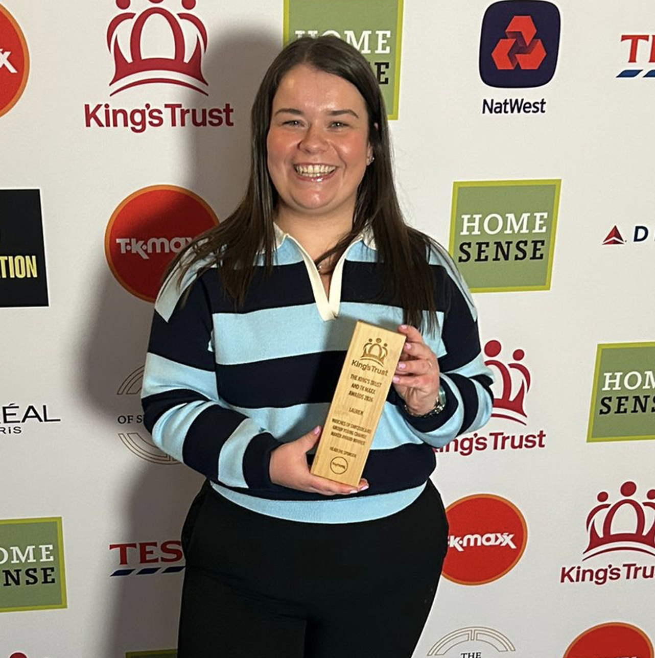 A person holding an award smiling at the camera