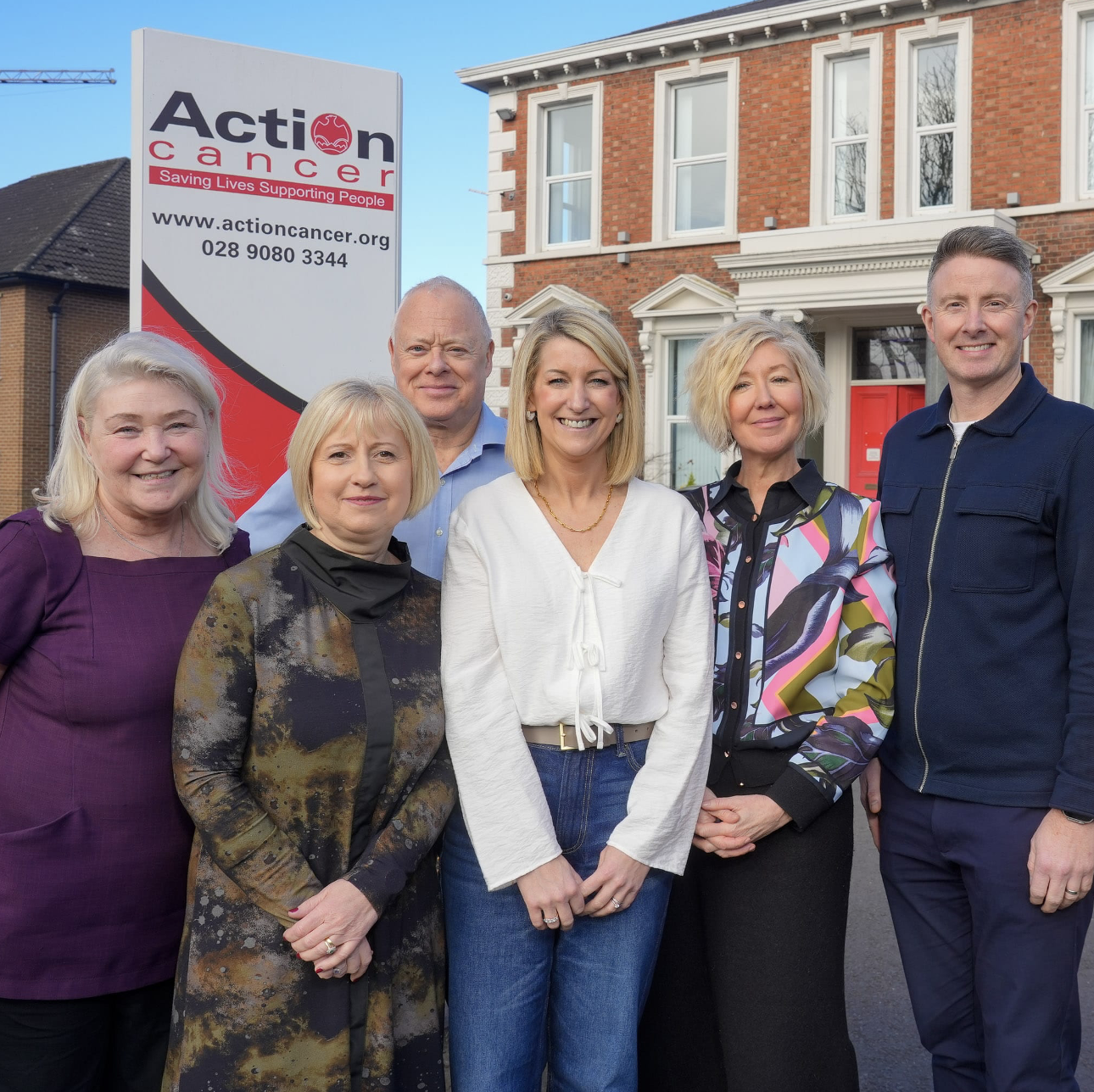 A group of people standing in front of an action cancer sign