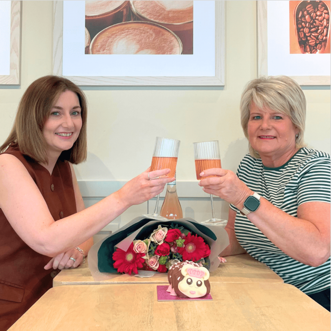 two people sat at a wooden table toasting with glasses of Prosecco