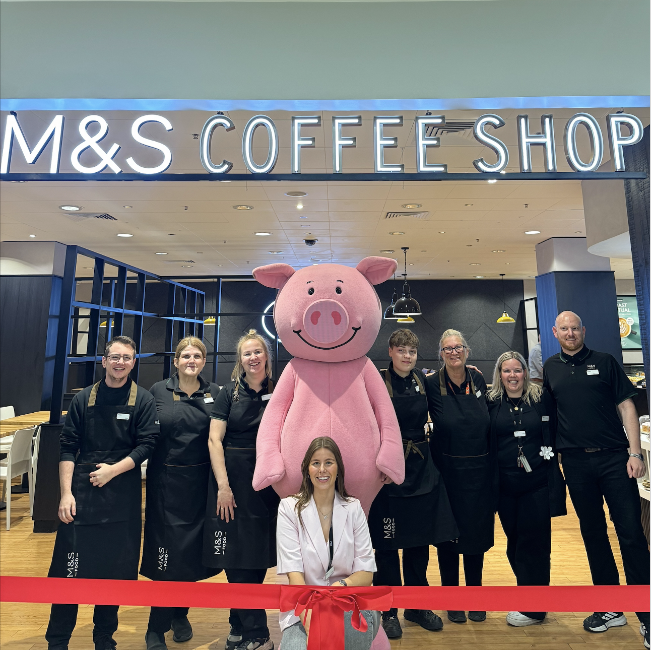 A crowd of people standing with a person in a pig mascot costume