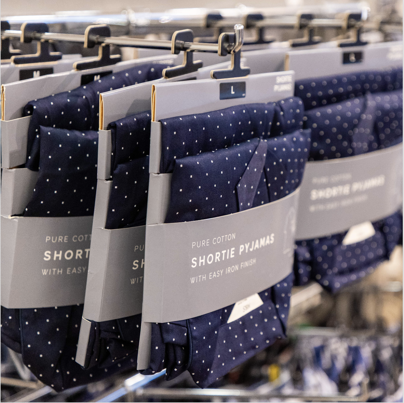 A shelf full of men's pyjamas hanging up in a shop