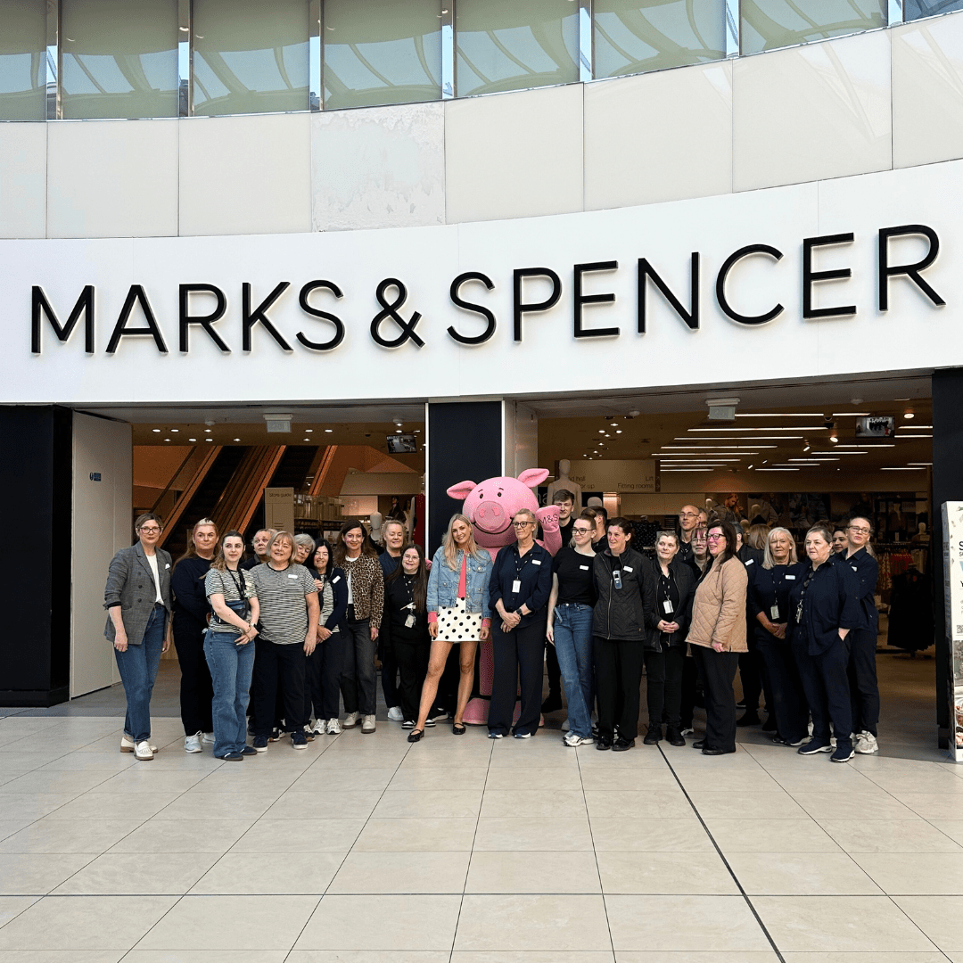 a group of people standing in front of a shop with a Marks and Spencer sign