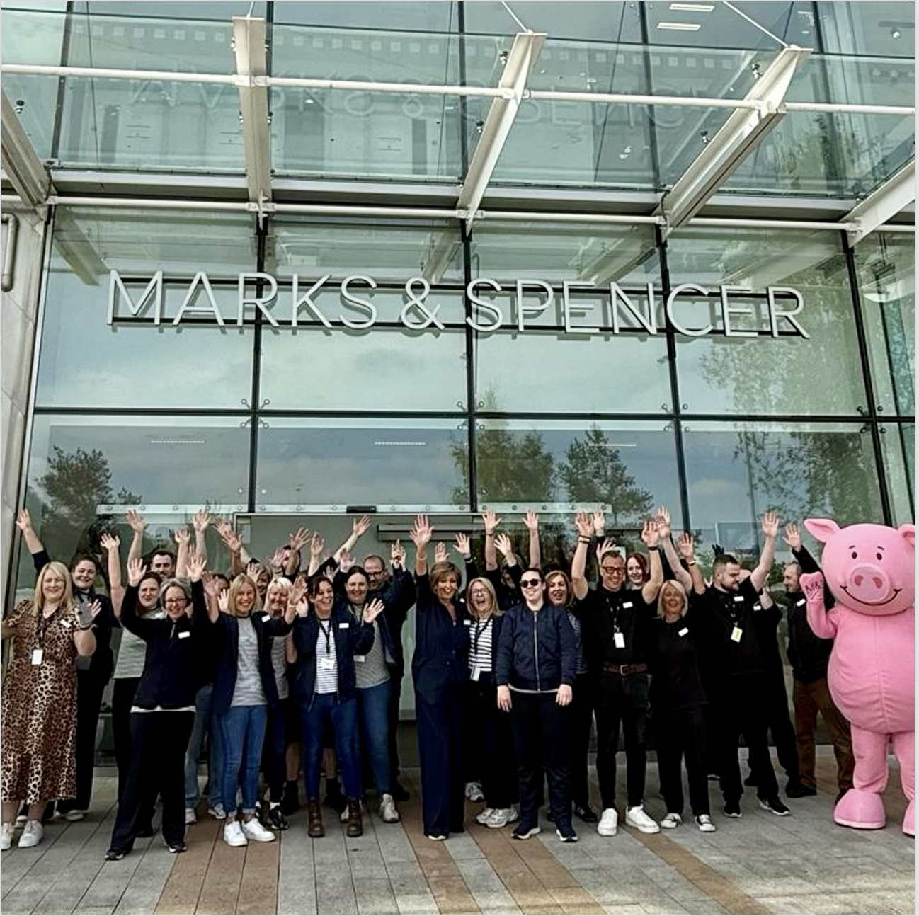 A group of people standing in front of a shop with a Marks and Spencer signople