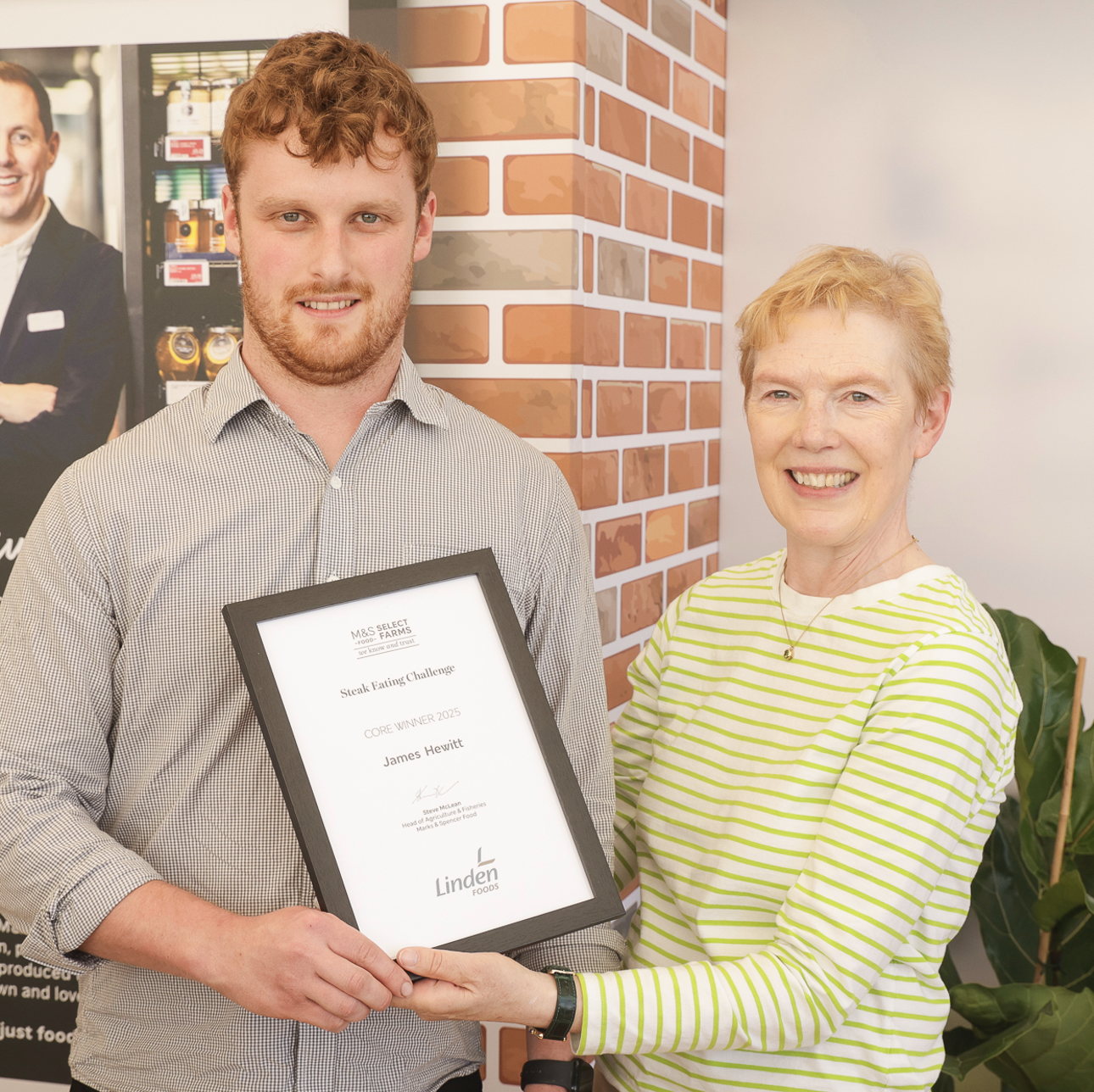 Two people shaking hands and smiling at the camera, one is holding a certificate