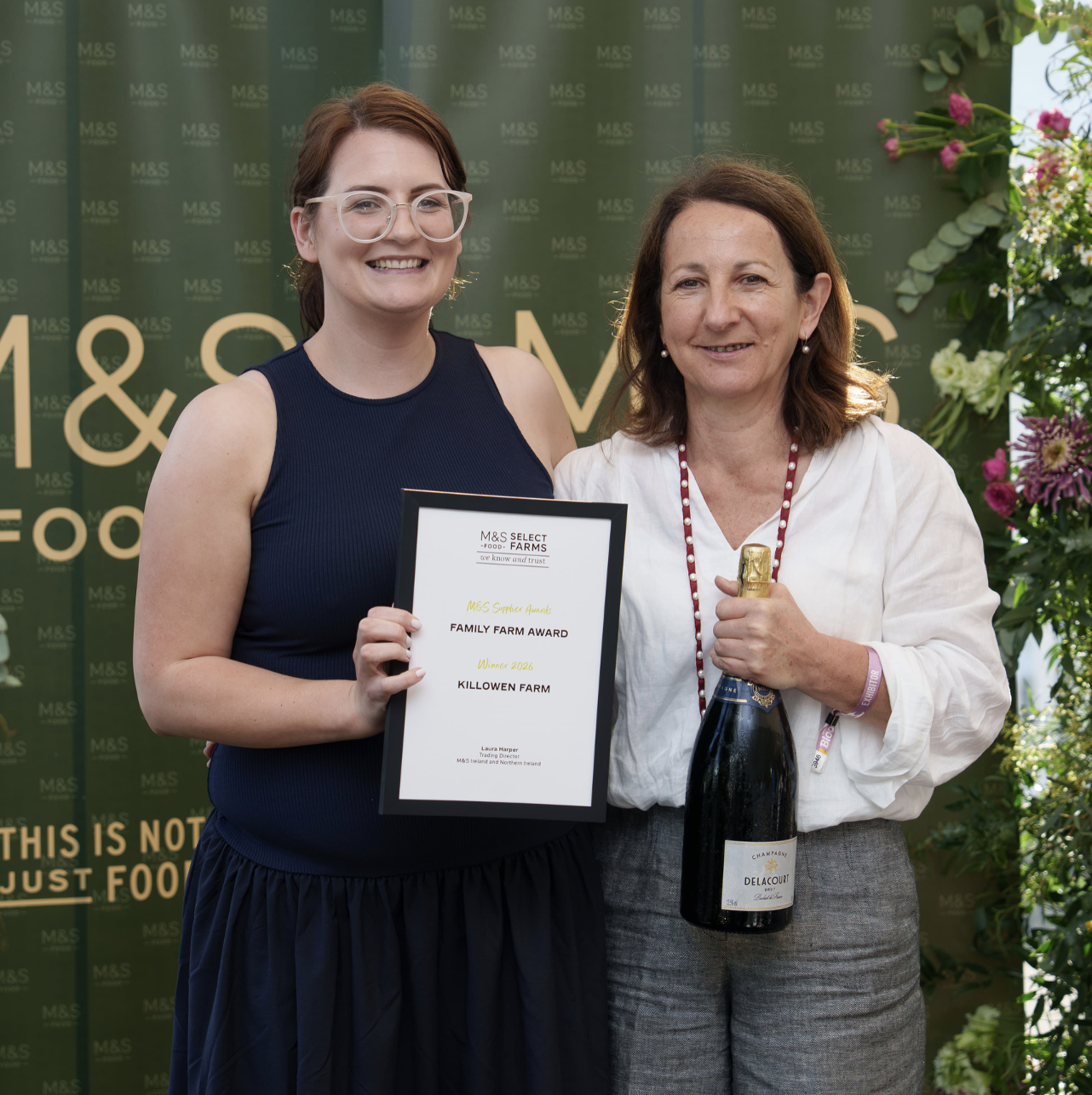 two people holding an award certificate and bottle of champagne