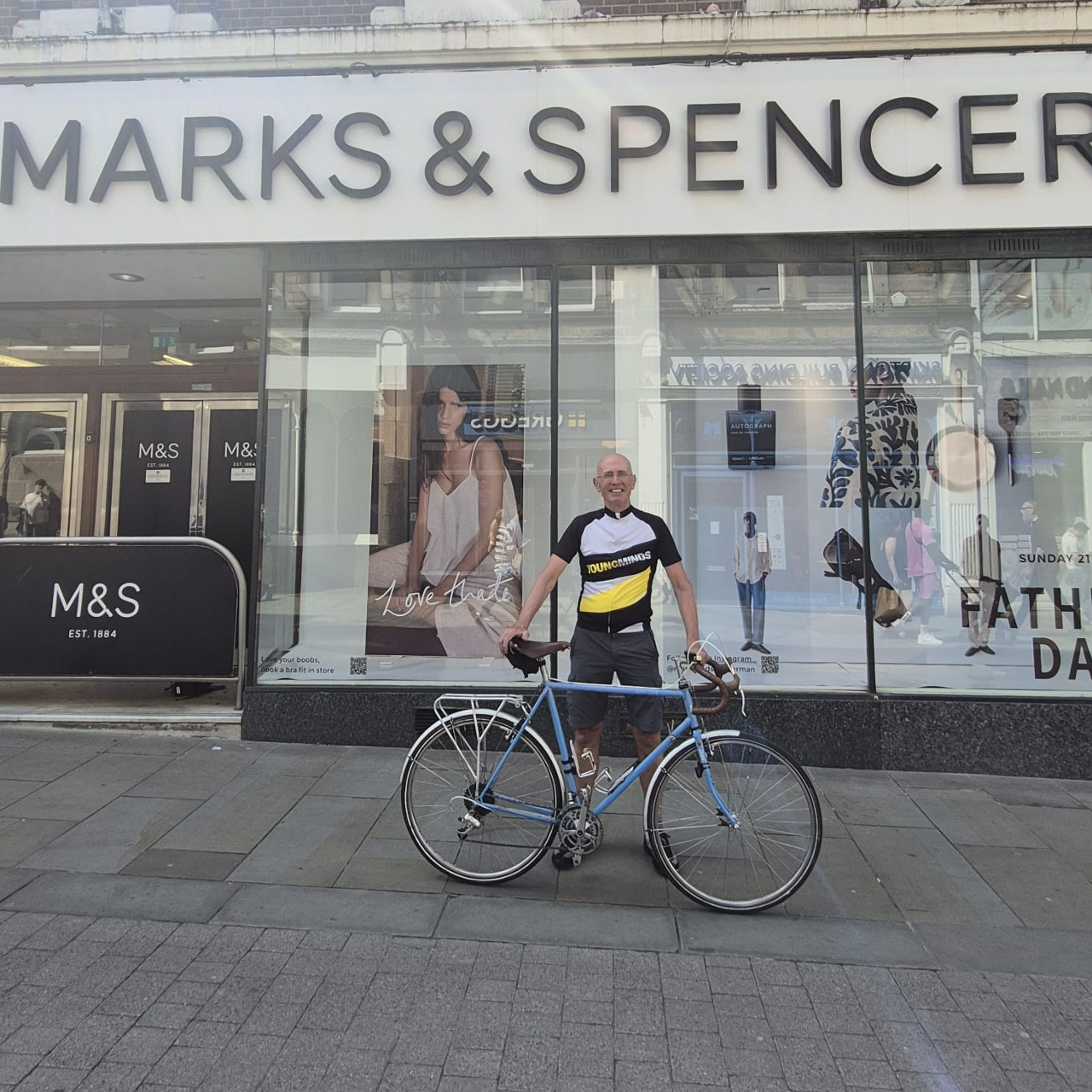 a person outside a Marks & Spencer store with a bicycle