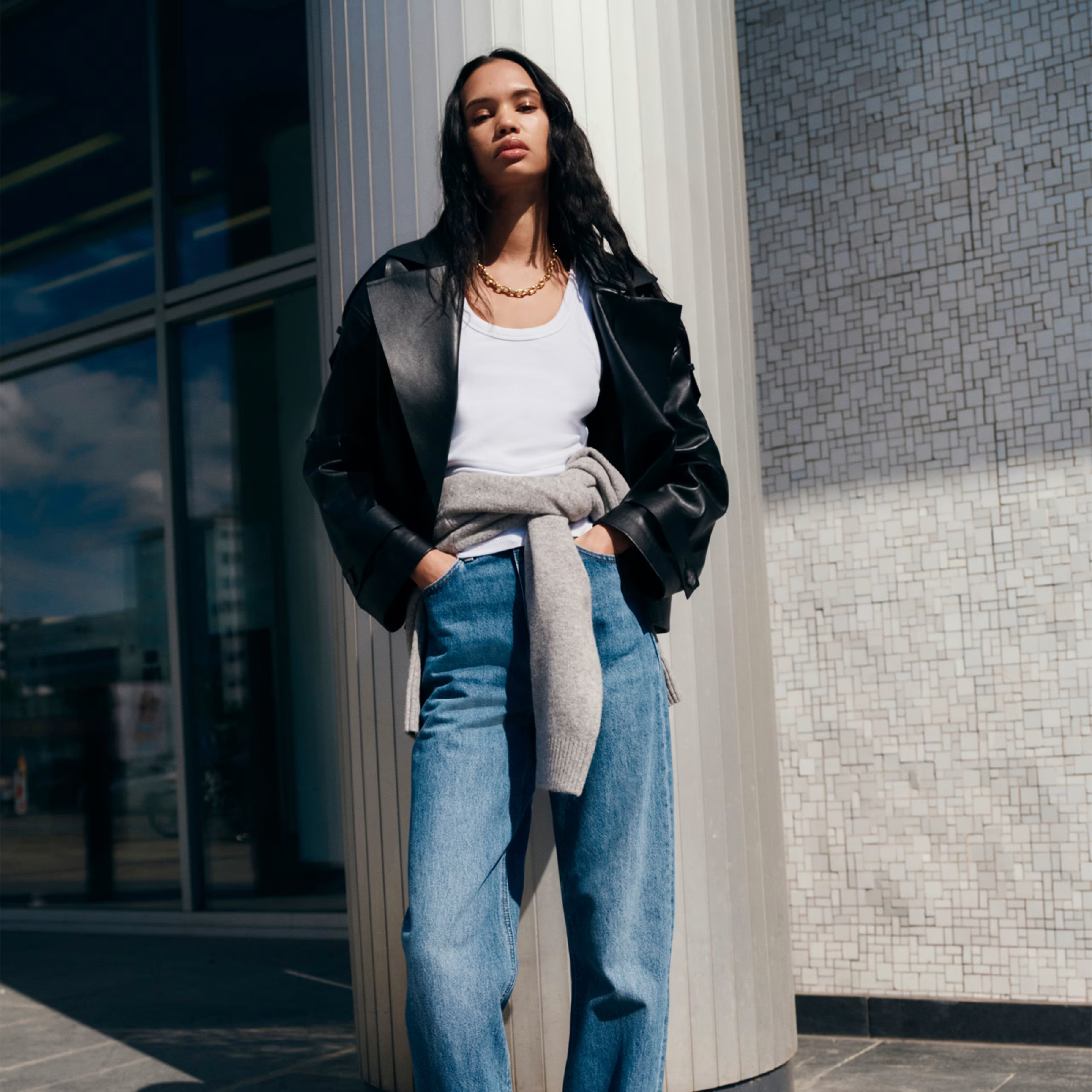 Woman standing wearing a leather jacket and jeans 