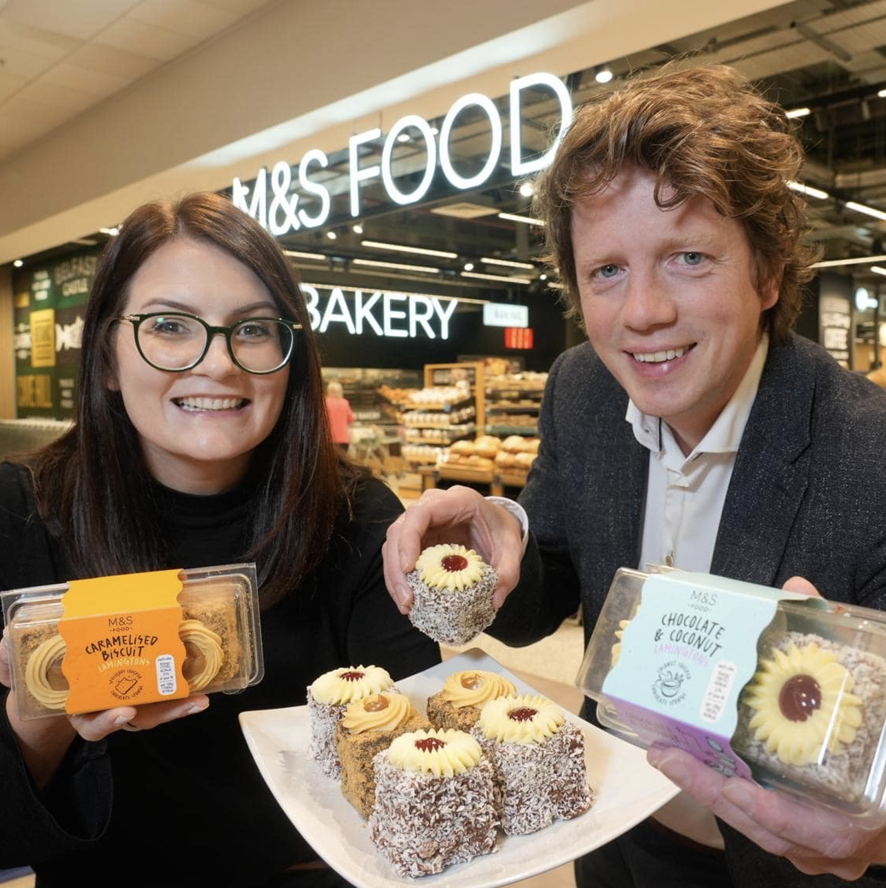 Two people in an M&S store holding square Lamington cakes