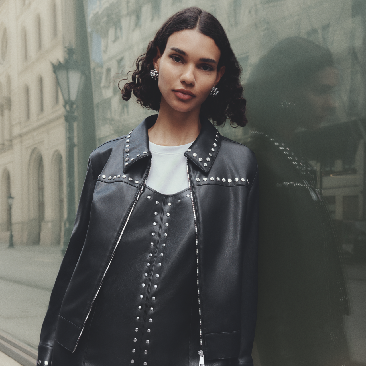A person wearing a black leather dress and matching jacket