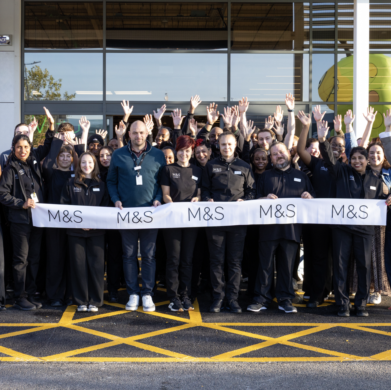 a group of people outside an M&S store