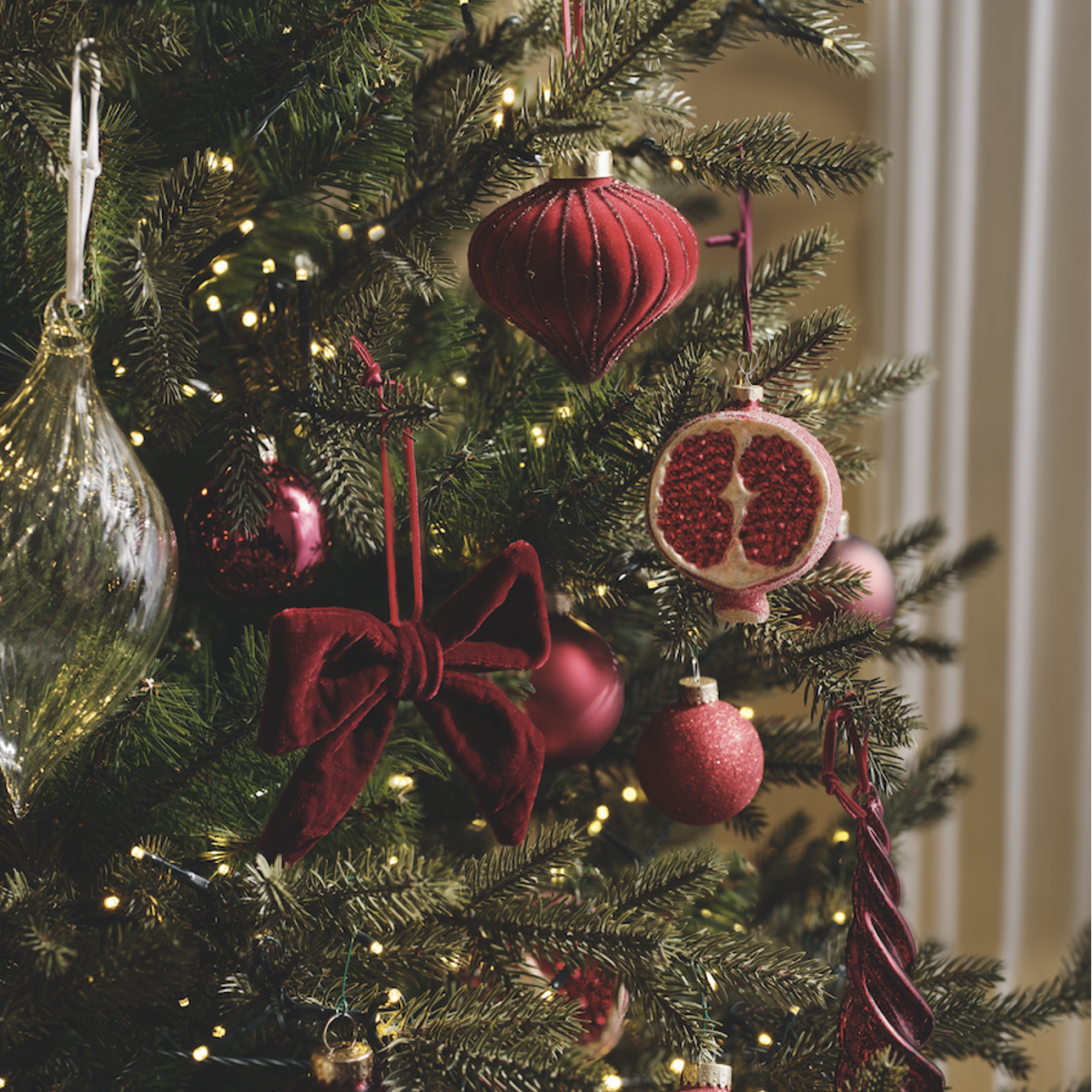 A green Christmas tree with red hanging decorations