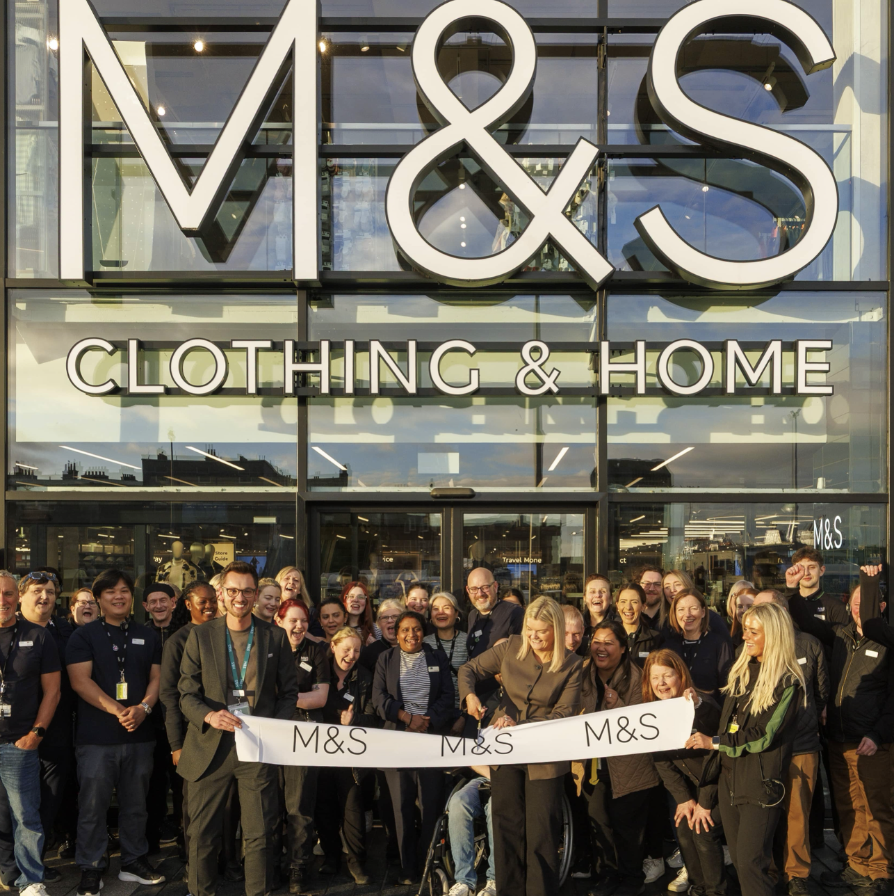a large group of people outside an M&S store