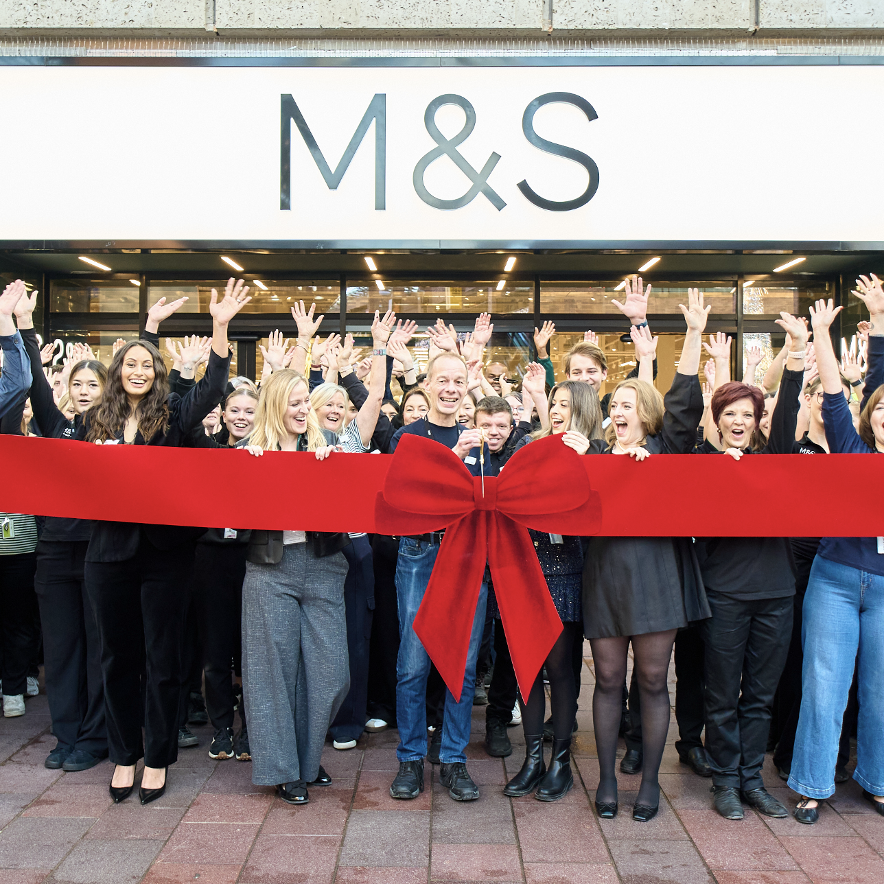 a group of people cutting a big red ribbon