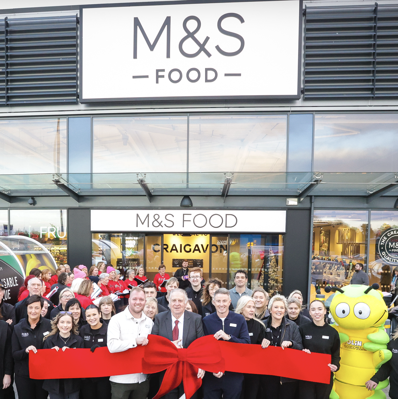 a group of people cutting a big red ribbonople
