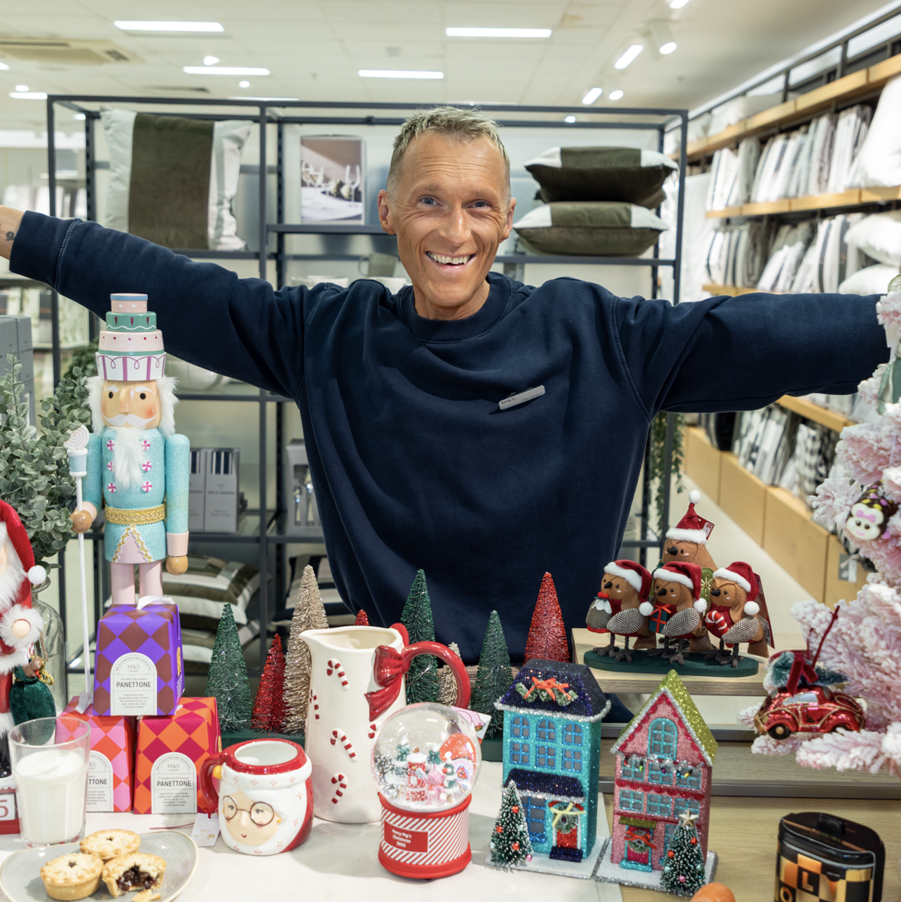 a person standing behind a table of Christmas ornaments