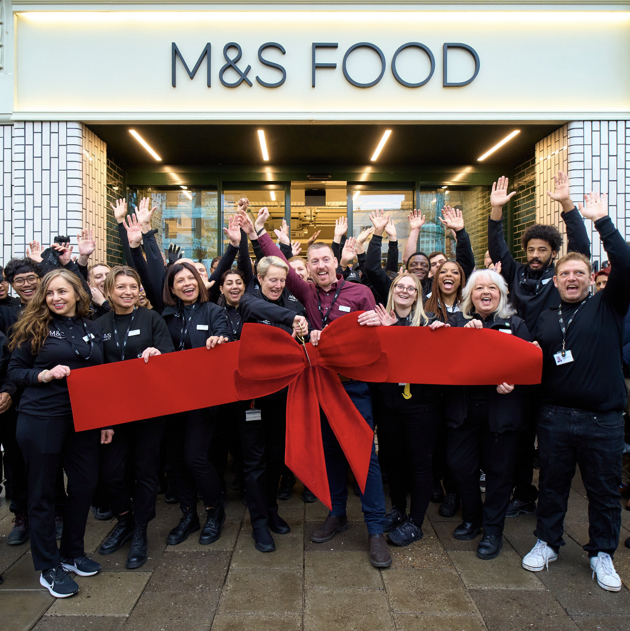 a group of people cutting a big red ribbonople