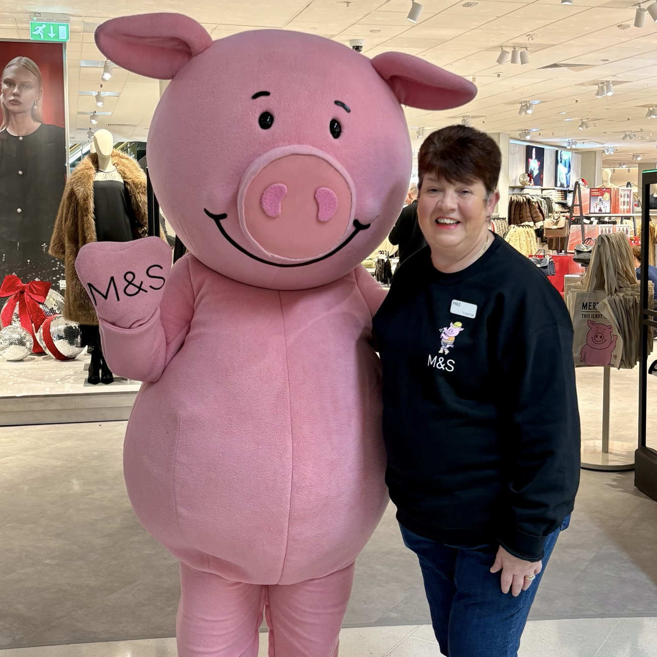 a person standing with a pink pig mascot