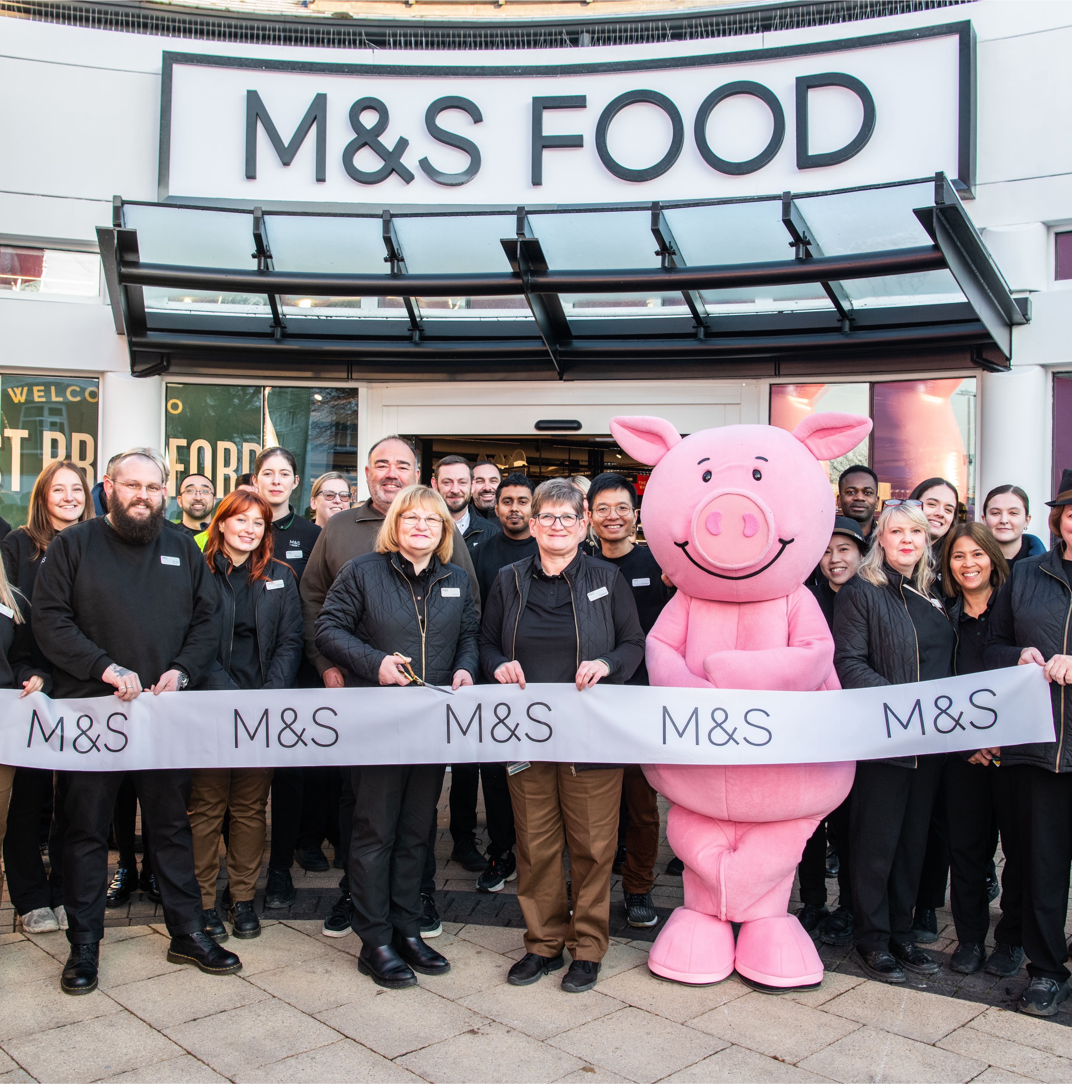 A group of people gathered outside an M&S store to cut the ribbon for opening day