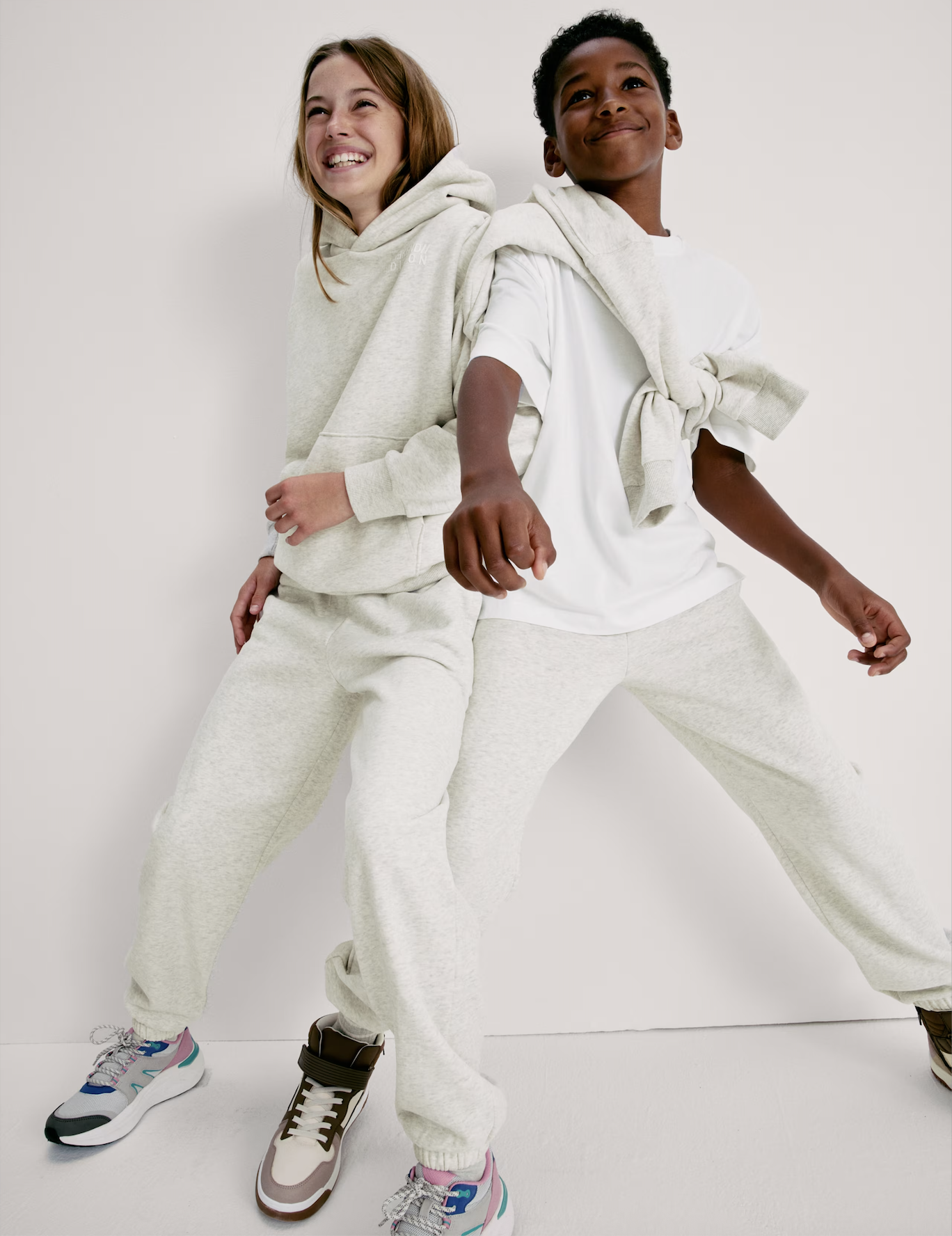 A young girl and boy wearing all white outfits and smiling