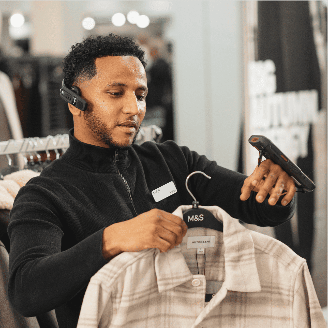 A person wearing a headset and working in a clothing shop